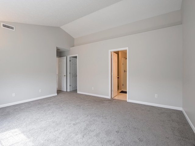 empty room featuring carpet floors, visible vents, vaulted ceiling, and baseboards