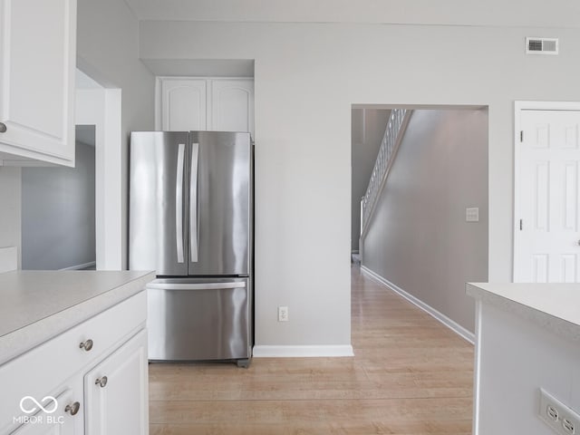 kitchen with visible vents, white cabinets, light wood-style flooring, freestanding refrigerator, and light countertops