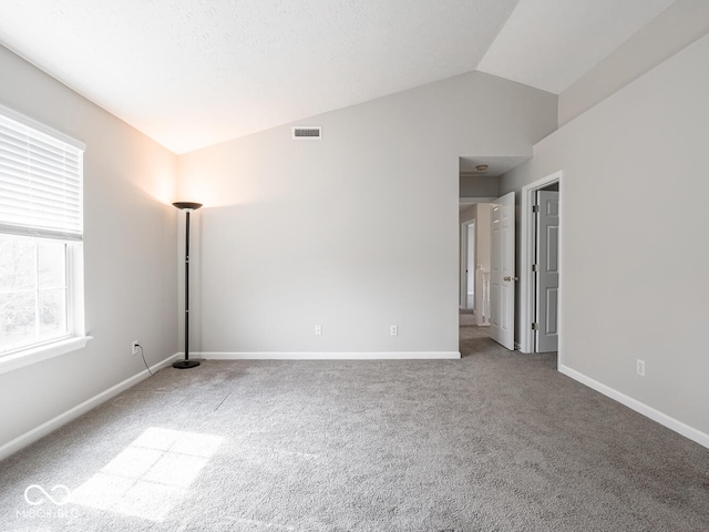 carpeted empty room with lofted ceiling, visible vents, and baseboards