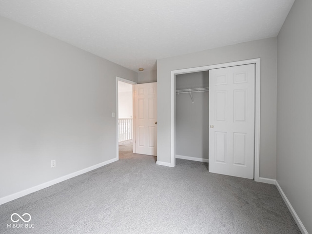 unfurnished bedroom featuring a closet, carpet flooring, a textured ceiling, and baseboards