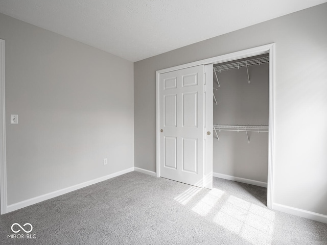 unfurnished bedroom with carpet floors, a closet, and baseboards