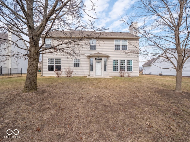 colonial home with a front yard, fence, and a chimney