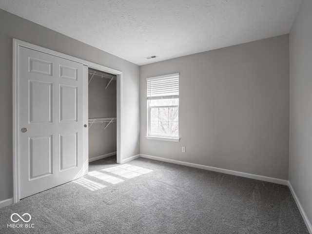 unfurnished bedroom featuring carpet floors, visible vents, a textured ceiling, and baseboards