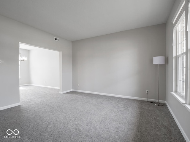 empty room with plenty of natural light, visible vents, and carpet flooring