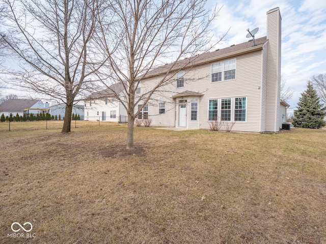 back of property with cooling unit, a lawn, and a chimney