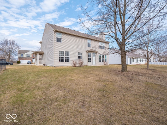 back of house with a chimney and a yard