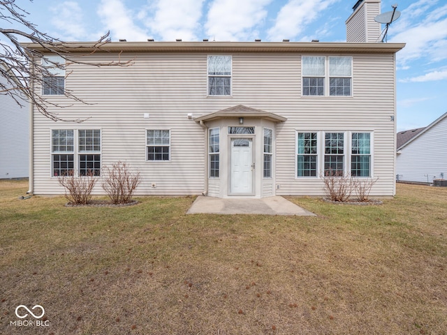 back of property featuring a lawn, a chimney, and central AC unit