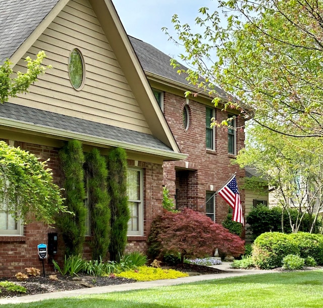 view of front of home with a shingled roof and brick siding