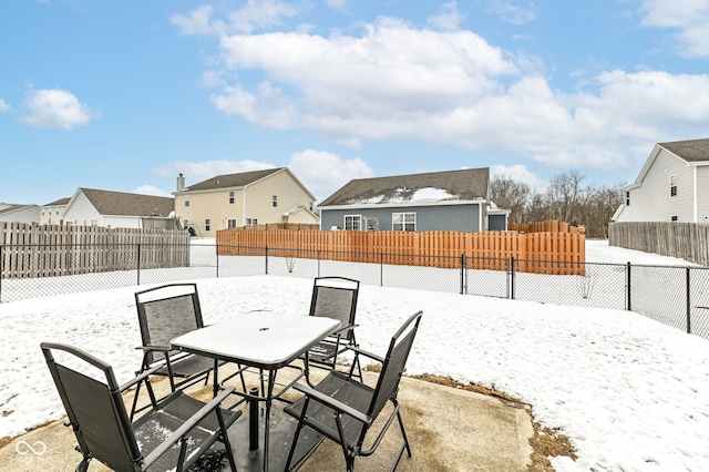 snow covered patio featuring a residential view and fence