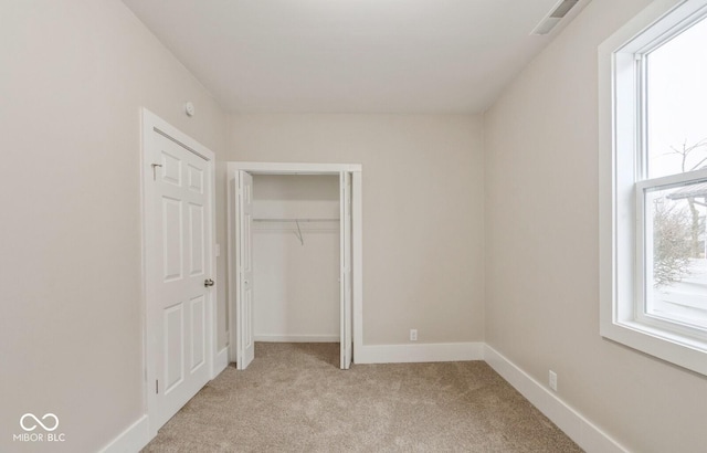 unfurnished bedroom featuring light colored carpet and a closet
