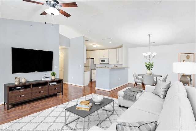 living area featuring dark wood-style floors, baseboards, and ceiling fan with notable chandelier