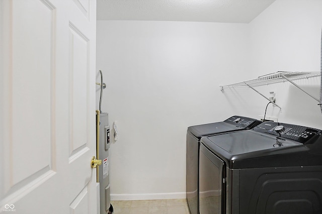 laundry room with laundry area, water heater, baseboards, and washer and clothes dryer