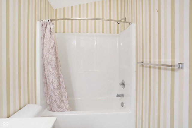 full bath featuring toilet, wallpapered walls, and shower / bath combo with shower curtain