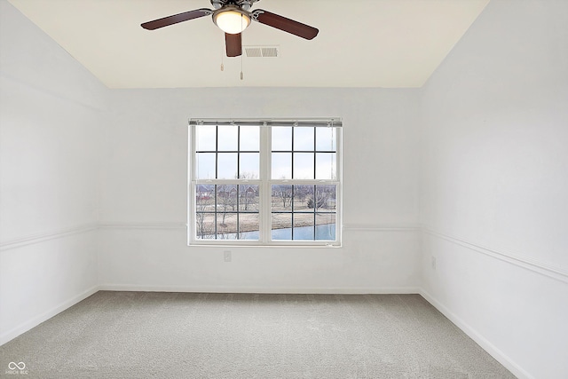 carpeted spare room featuring a ceiling fan, visible vents, and baseboards