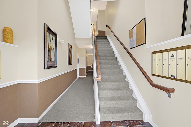 staircase with a high ceiling, mail area, and baseboards