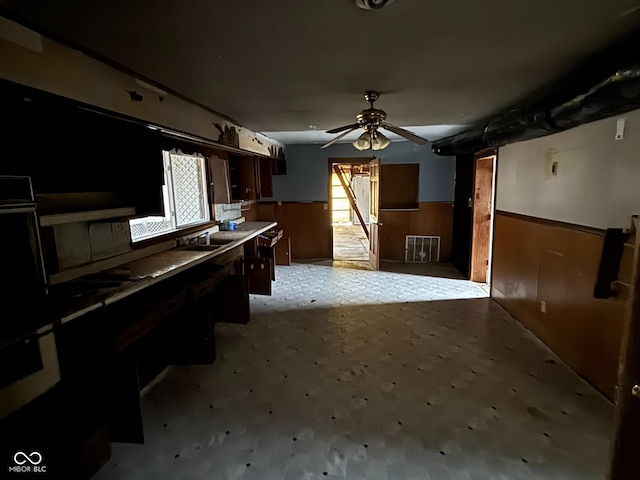 kitchen featuring ceiling fan and wood walls