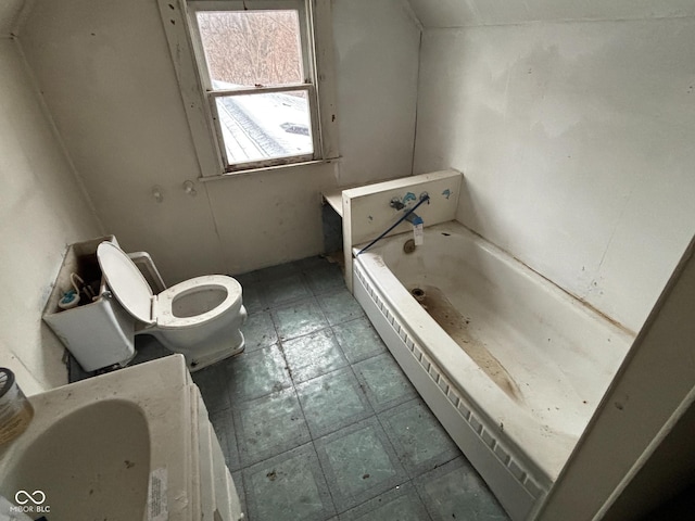 bathroom with lofted ceiling, a washtub, and toilet