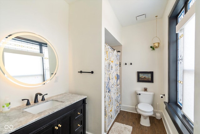 bathroom with visible vents, baseboards, toilet, wood finished floors, and vanity