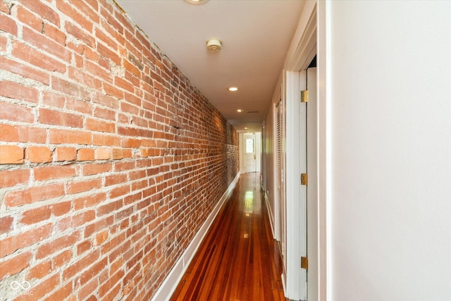 hall with baseboards, brick wall, wood finished floors, and recessed lighting