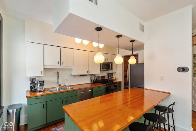 kitchen with pendant lighting, appliances with stainless steel finishes, white cabinets, a sink, and green cabinetry