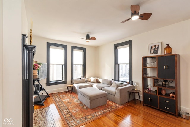 living area with baseboards, a ceiling fan, and wood finished floors