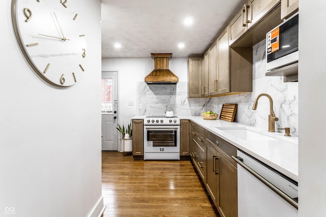 kitchen with premium range hood, sink, stainless steel range, white dishwasher, and dark hardwood / wood-style flooring