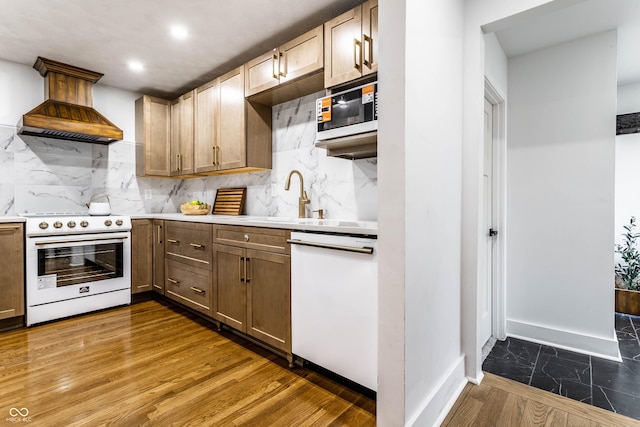 kitchen with dark hardwood / wood-style floors, sink, decorative backsplash, custom range hood, and white appliances