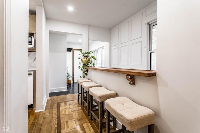 interior space featuring dark parquet flooring, a breakfast bar area, and a wealth of natural light