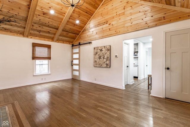 spare room with wood ceiling, dark wood-type flooring, beam ceiling, high vaulted ceiling, and a barn door