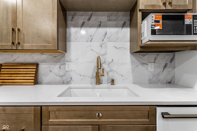 kitchen with sink, backsplash, light stone countertops, and dishwasher