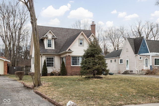 cape cod home with entry steps, brick siding, fence, and a front yard