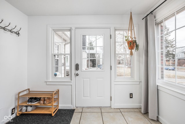 doorway to outside featuring light tile patterned flooring, a wealth of natural light, and baseboards