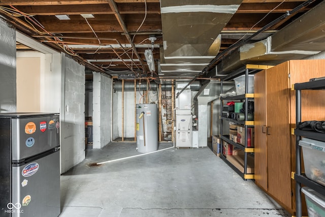 unfinished basement with heating unit, water heater, and freestanding refrigerator