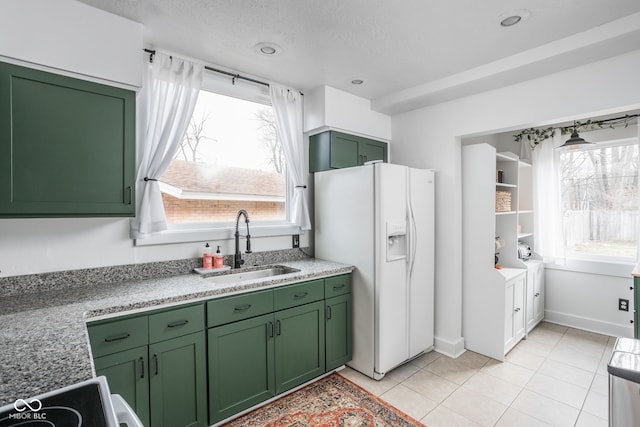 kitchen featuring plenty of natural light, white fridge with ice dispenser, green cabinets, and a sink