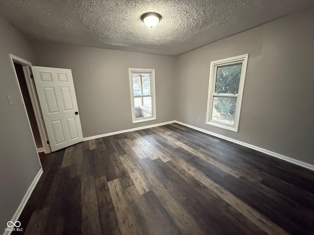 unfurnished room featuring dark wood-type flooring and a textured ceiling