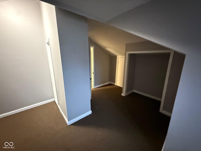 additional living space featuring lofted ceiling and dark carpet