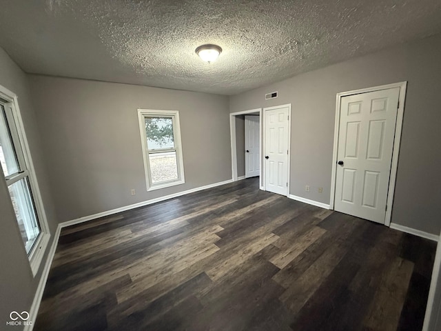 unfurnished bedroom featuring dark hardwood / wood-style floors and a textured ceiling