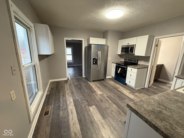 kitchen featuring white cabinetry, appliances with stainless steel finishes, dark hardwood / wood-style flooring, and a textured ceiling