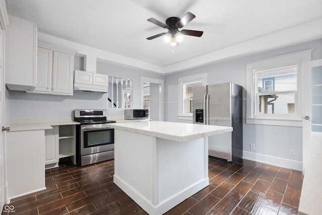 kitchen featuring stainless steel appliances, white cabinetry, a kitchen island, and ceiling fan