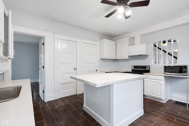 kitchen with white cabinetry, a kitchen island, light stone countertops, and appliances with stainless steel finishes