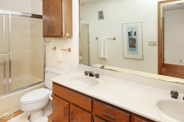 bathroom featuring toilet, double vanity, a sink, and visible vents