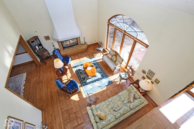 living area featuring baseboards, a fireplace, and a high ceiling