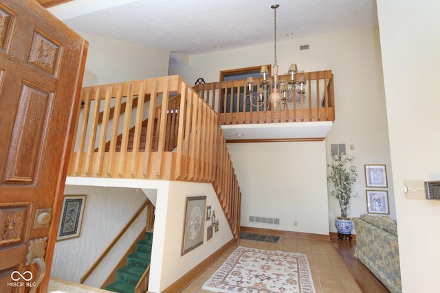 stairs featuring a notable chandelier, visible vents, a textured ceiling, and tile patterned floors