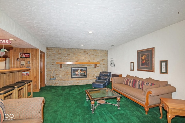 carpeted living room featuring a bar, recessed lighting, a stone fireplace, and a textured ceiling