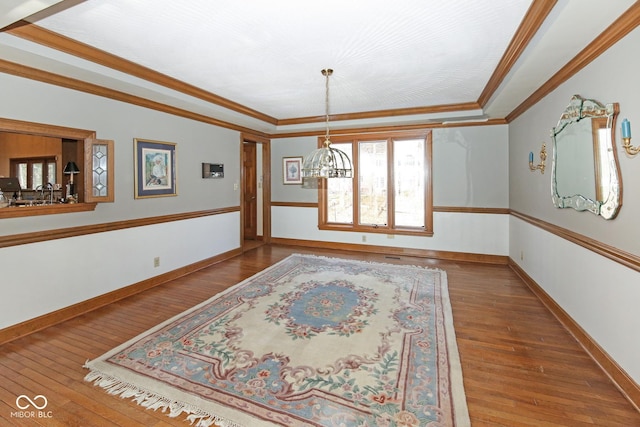 unfurnished dining area with wood-type flooring, ornamental molding, and baseboards