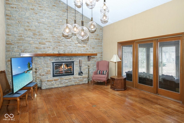 unfurnished room featuring hardwood / wood-style flooring, high vaulted ceiling, and a stone fireplace