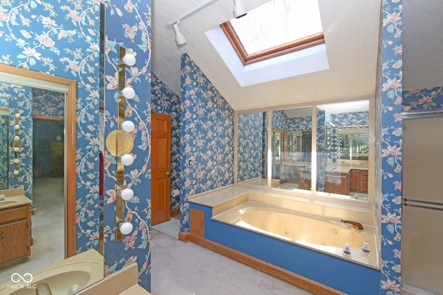 bathroom with a whirlpool tub, wallpapered walls, lofted ceiling with skylight, and vanity