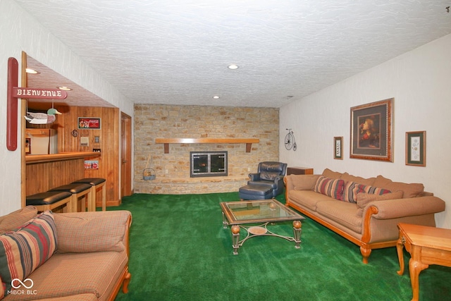 living room with carpet floors, a stone fireplace, and a textured ceiling