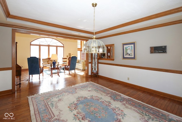 interior space featuring ornamental molding, a tray ceiling, hardwood / wood-style floors, and baseboards