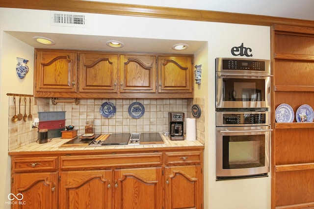 kitchen featuring tile countertops, tasteful backsplash, visible vents, and stainless steel double oven